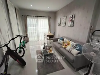 Cozy living room with modern decor, featuring a comfortable sofa, stylish artwork, and natural light from large windows.