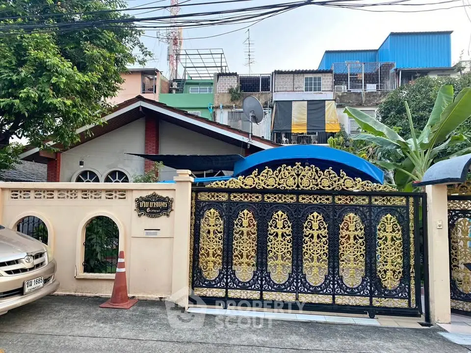 Charming residential property with ornate gate and lush greenery in urban setting.