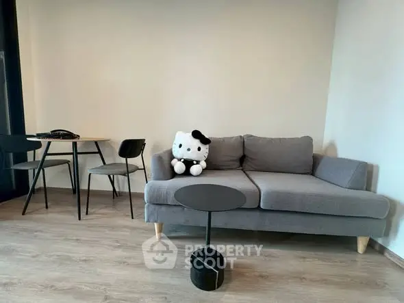Modern living room with stylish gray sofa and chic black table set on wooden flooring.