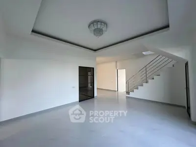 Spacious modern living room with elegant staircase and chandelier