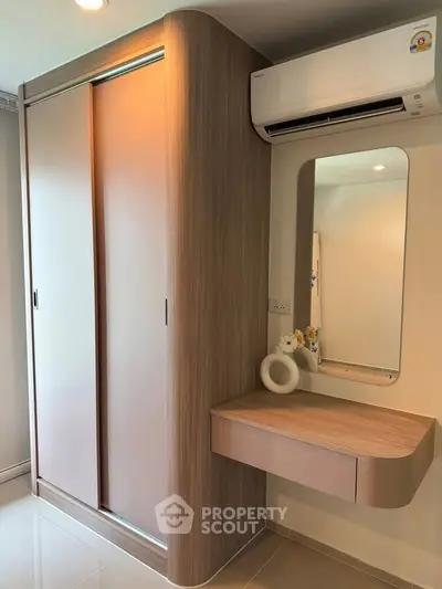 Modern bedroom with sleek wardrobe and wall-mounted vanity under air conditioning unit.