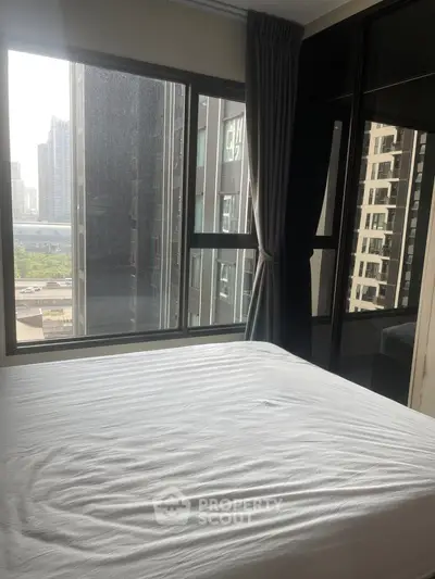 Spacious bedroom with large windows offering a stunning city view, perfect for urban living.