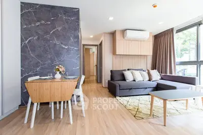 Modern living room with stylish decor and natural light, featuring a cozy sofa and dining area.