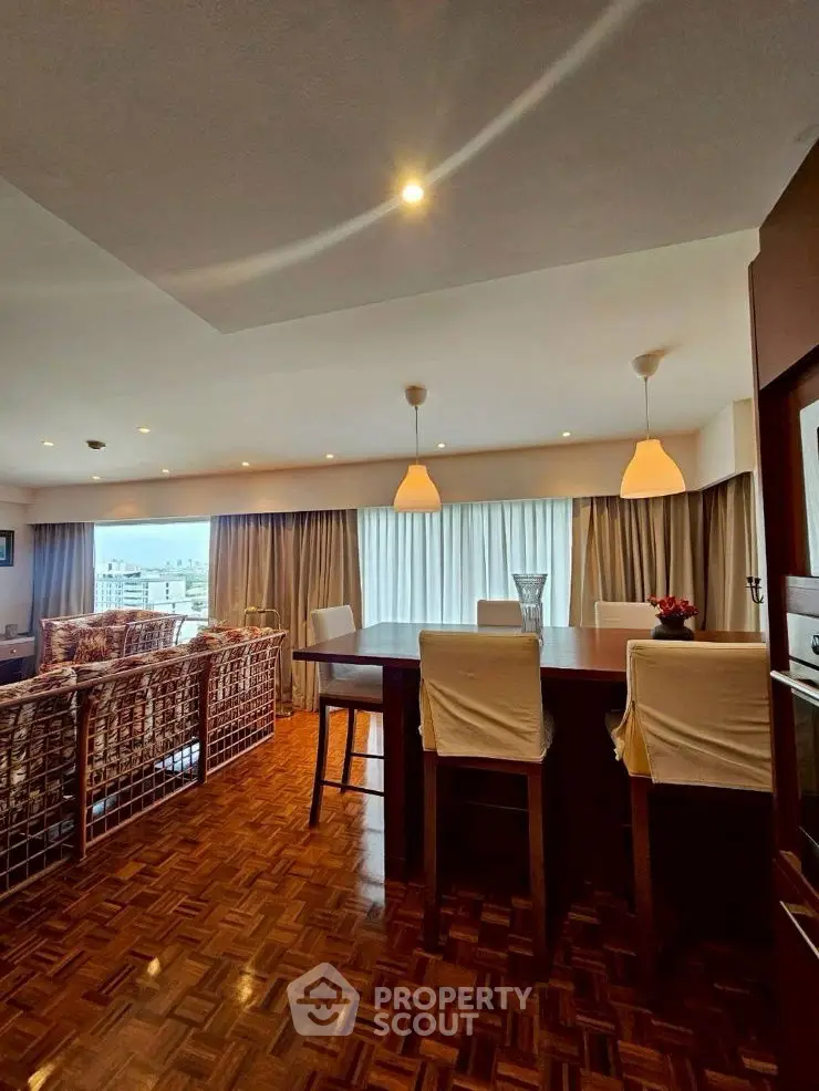 Spacious open-plan living and dining area with elegant lighting and city view.