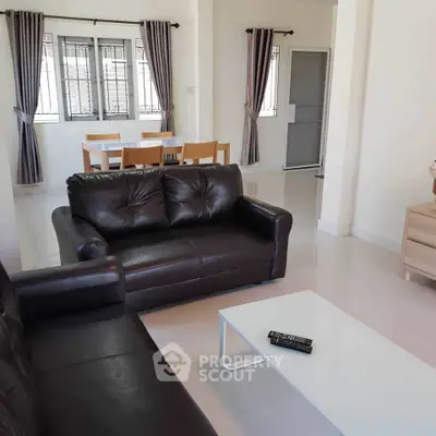 Spacious living room with modern leather sofas and dining area, perfect for relaxation and entertaining.