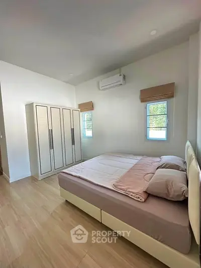 Spacious bedroom with modern decor and ample natural light, featuring a comfortable bed and stylish wardrobe.