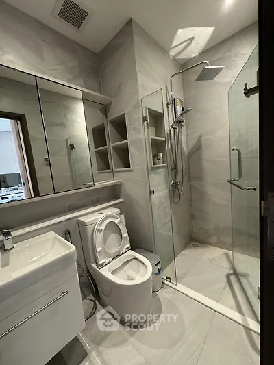 Modern bathroom with sleek fixtures and glass shower enclosure in a contemporary apartment.