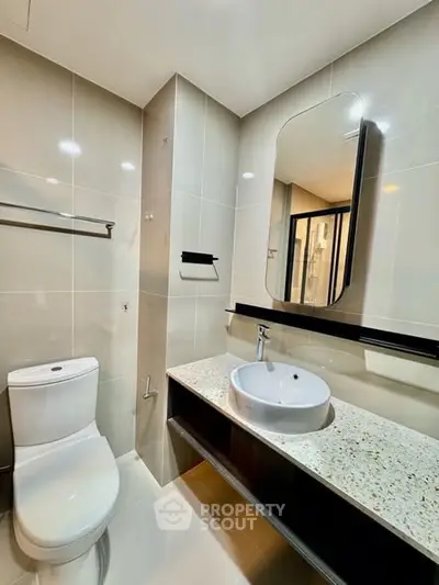 Modern bathroom with sleek fixtures and elegant design, featuring a stylish mirror and contemporary sink.