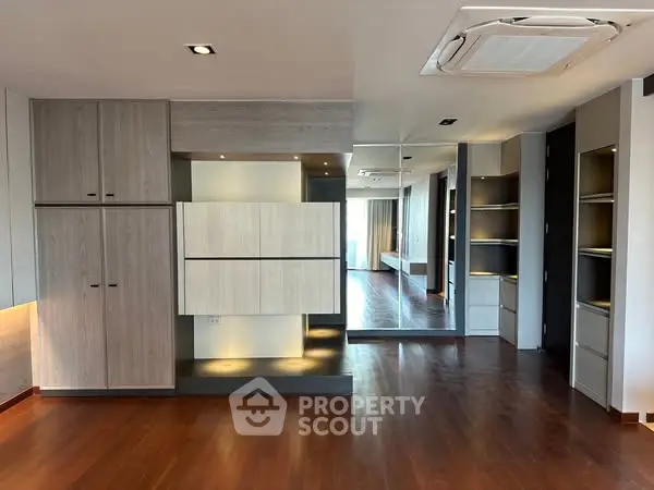 Spacious modern living room with wooden flooring and built-in storage solutions.