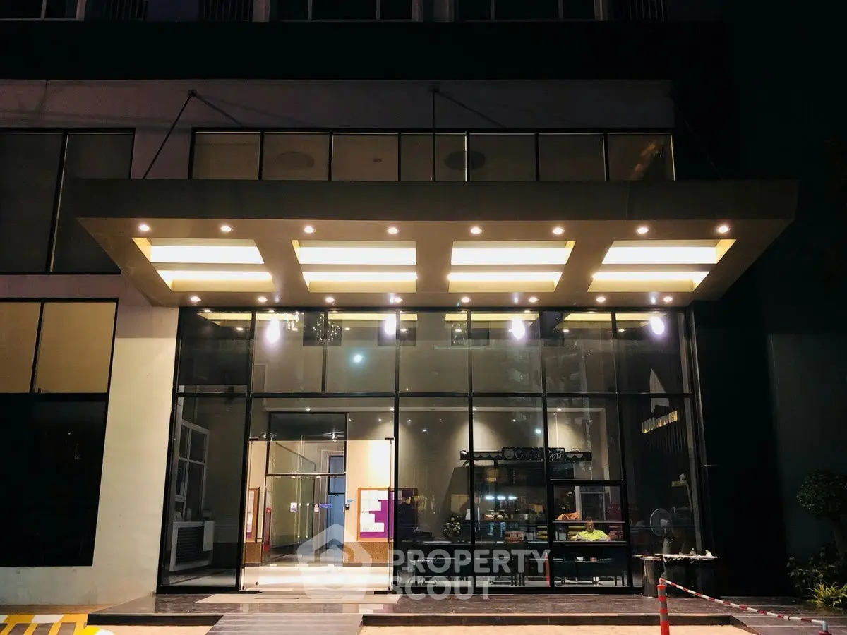 Modern building entrance with sleek glass facade and illuminated canopy