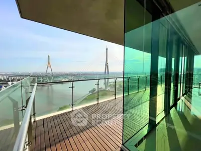 Stunning balcony view with glass railing overlooking a river and iconic bridge, perfect for relaxation.