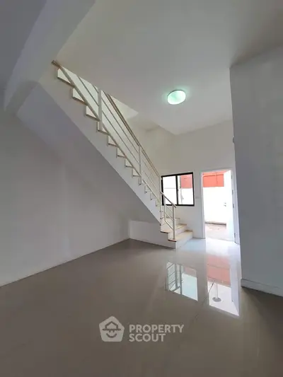 Spacious modern interior with sleek staircase and glossy floors, perfect for contemporary living.