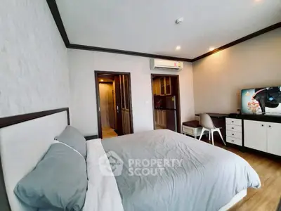 Spacious bedroom with modern decor and adjacent kitchenette in a stylish apartment.