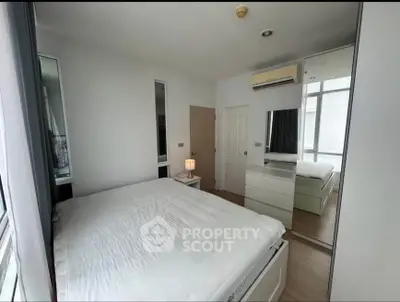 Modern bedroom with large mirror and air conditioning, featuring minimalistic design and ample natural light.