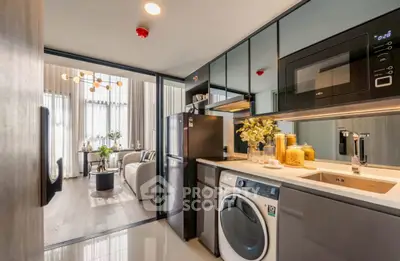 Modern kitchen with sleek appliances and open layout leading to a stylish living room.