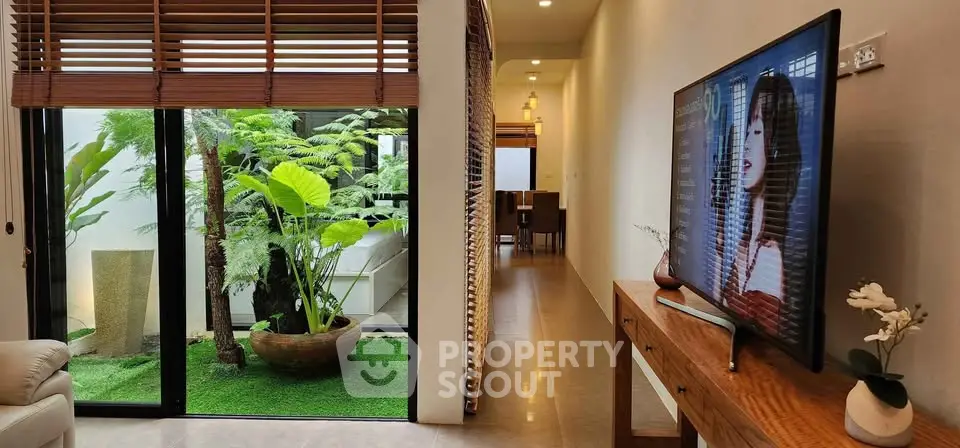 Modern living room with large TV, indoor garden, and stylish decor in a contemporary home.
