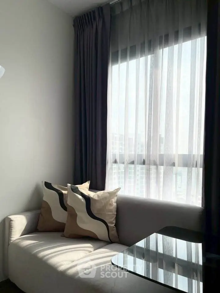 Cozy living room with modern sofa and large window, perfect for relaxation.