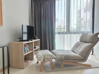 Modern living room with cozy lounge chair and TV setup, featuring large windows and elegant curtains.
