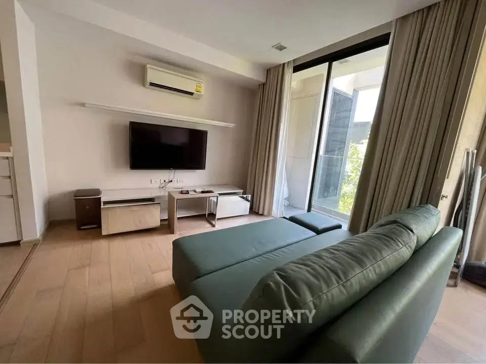 Modern living room with sleek furniture and large window offering natural light.