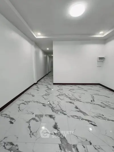Spacious modern interior with elegant marble flooring and recessed lighting, perfect for versatile living space.