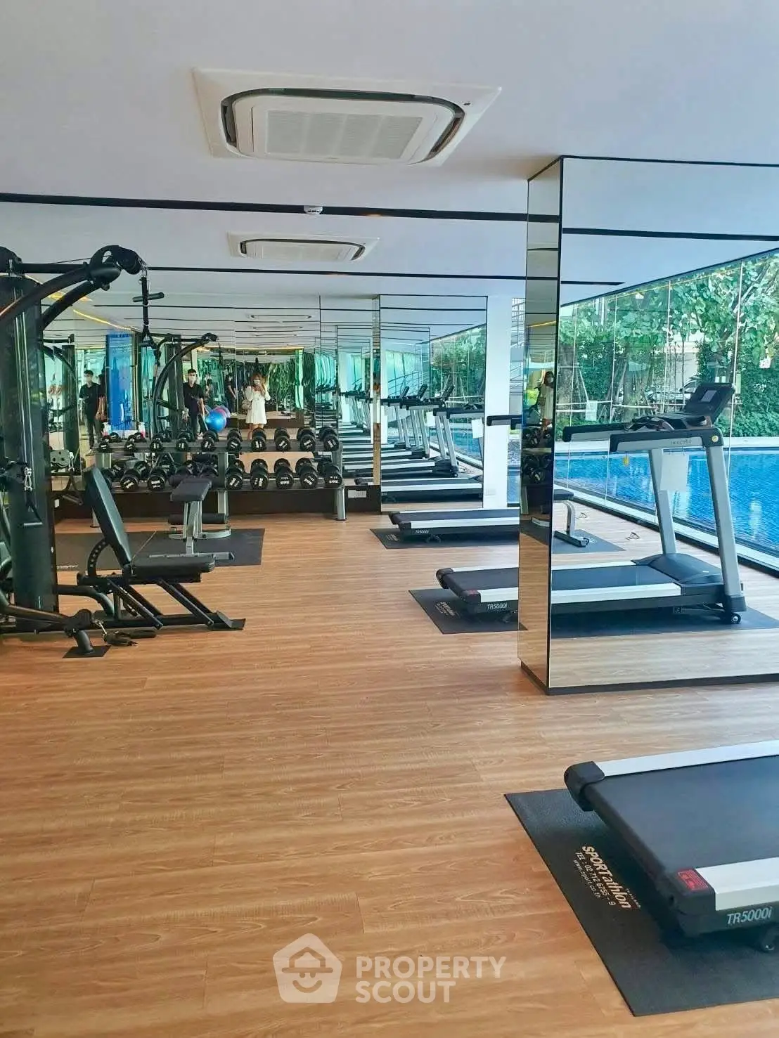 Modern gym with state-of-the-art equipment and pool view in luxury real estate property.