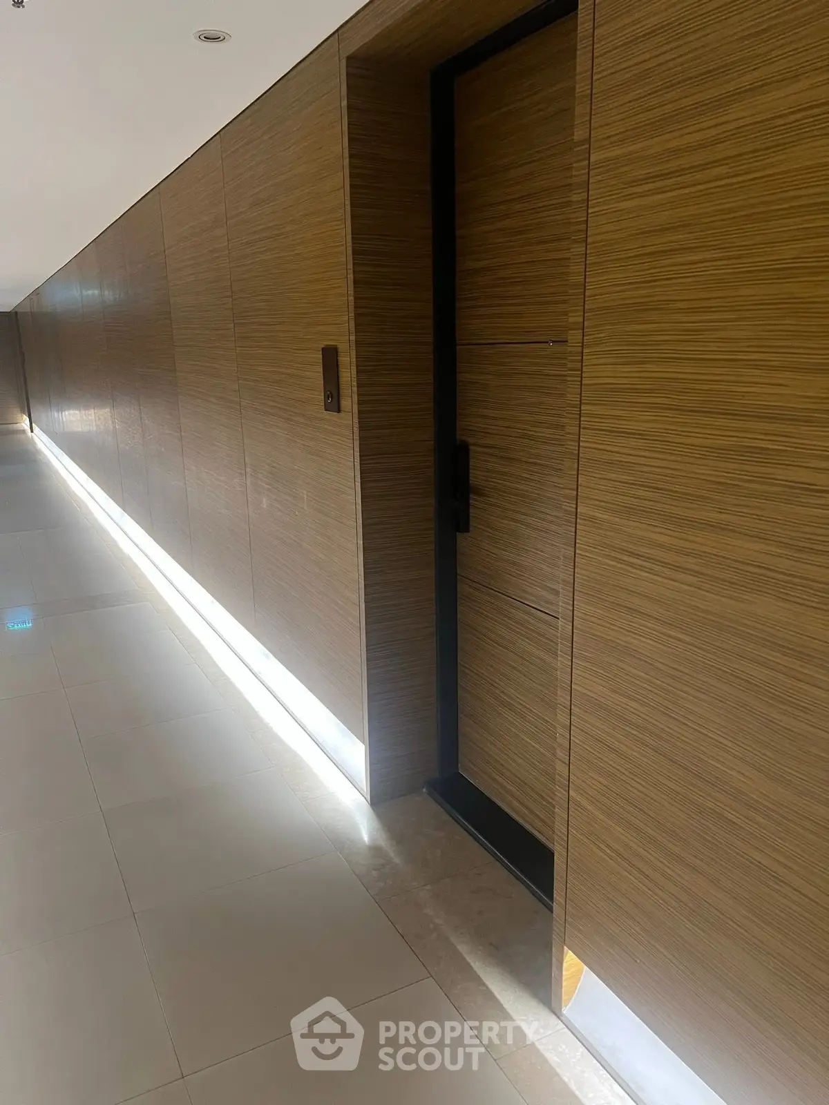 Sleek modern corridor with wooden paneling and ambient lighting in luxury building.