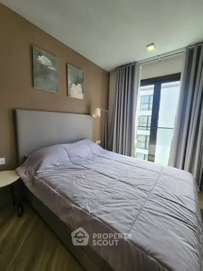 Modern bedroom with stylish decor and large window offering natural light and a view of the cityscape.