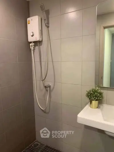 Modern bathroom with electric shower and sleek tile design, perfect for contemporary living.