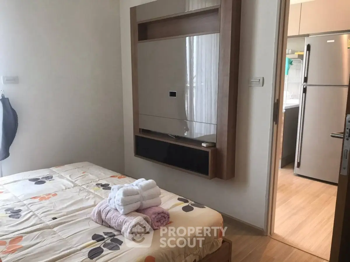Cozy bedroom with modern decor and view into a sleek kitchen area.