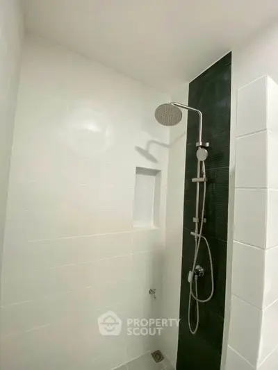 Modern bathroom with sleek shower design and minimalist white tiles.