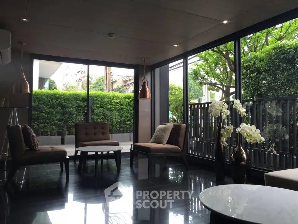 Elegant living room with modern furniture and large windows overlooking lush greenery.