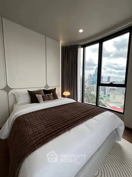 Luxurious bedroom with stunning city view from large windows, featuring elegant decor and cozy bedding.