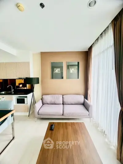 Modern living room with cozy sofa and large window, open kitchen layout.