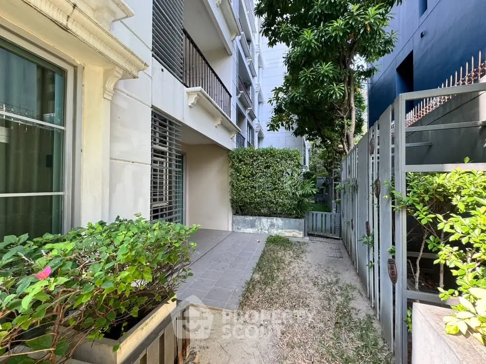 Charming urban garden space with lush greenery and modern building facade, perfect for relaxation and outdoor activities.