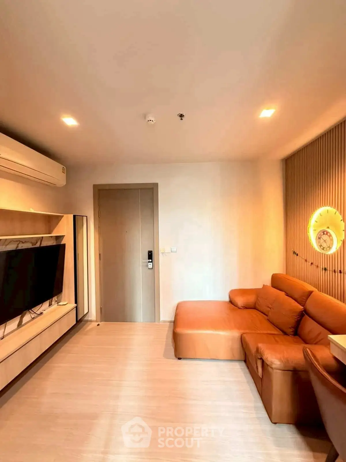 Modern living room with leather sofa and wall-mounted TV in stylish apartment.