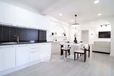 Modern open-layout kitchen and dining area with sleek white cabinets and stylish decor.