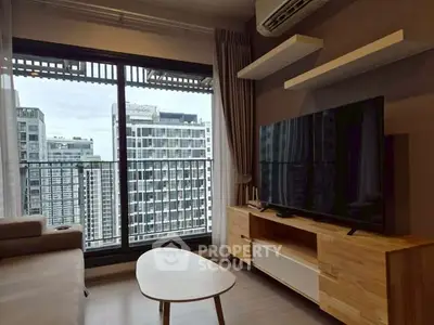 Modern living room with large TV and city view from balcony in high-rise apartment.