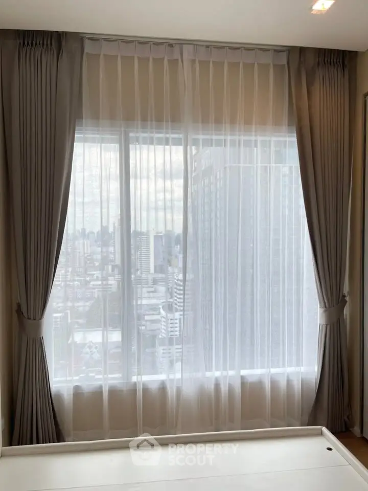 Spacious apartment window with city view and elegant curtains