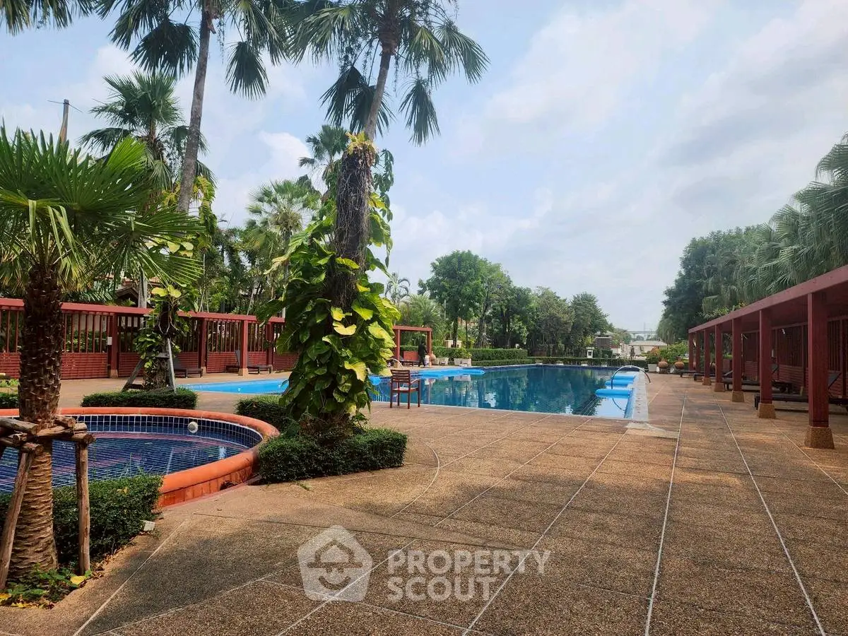 Luxurious outdoor pool area with lush greenery and palm trees, perfect for relaxation and leisure.