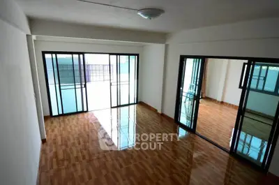 Spacious living room with wooden flooring and large windows for natural light.