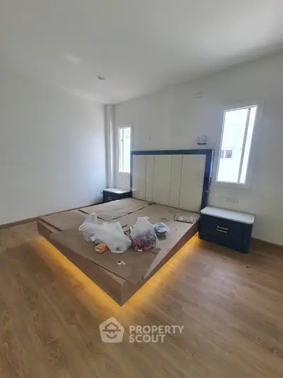 Modern bedroom with wooden flooring and built-in lighting under bed frame
