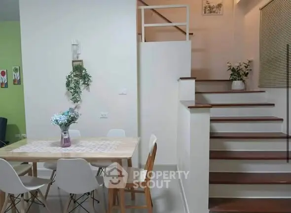 Charming dining area with modern decor and elegant staircase in cozy home interior.
