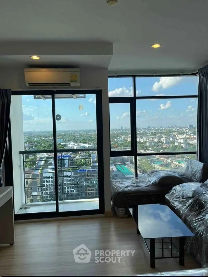 Modern living room with stunning city view and balcony access in high-rise apartment.