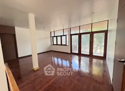 Spacious empty room with large windows and wooden flooring, perfect for customization.