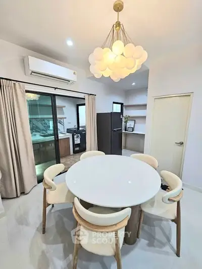 Modern dining area with elegant chandelier and open kitchen layout in a stylish apartment.