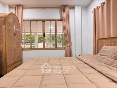 Cozy bedroom with large window and elegant wooden furniture, offering a serene and inviting atmosphere.