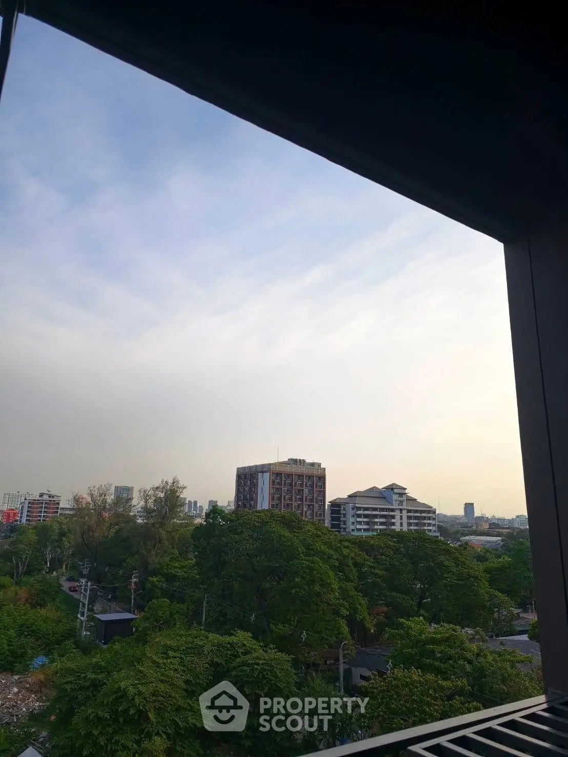 Stunning cityscape view from a high-rise balcony overlooking lush greenery and urban skyline.