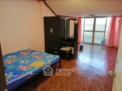 Spacious bedroom with wooden flooring and large window for natural light.