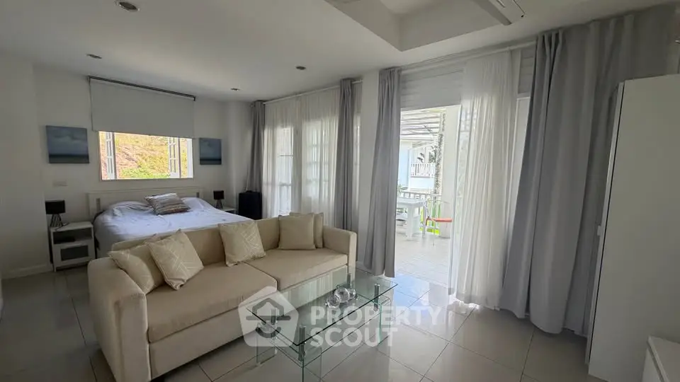 Spacious modern bedroom with large windows and balcony access, featuring elegant decor and natural light.