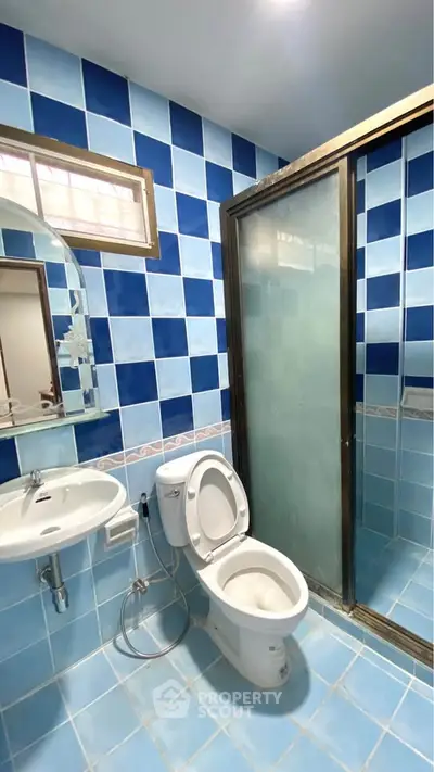 Modern bathroom with blue tiles, glass shower, and sleek fixtures.